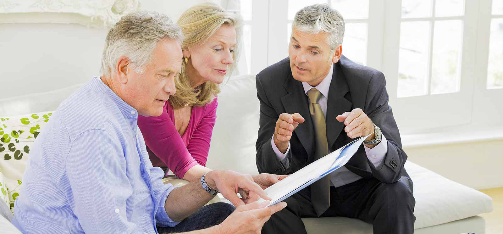 Mature couple sitting on sofa with financial advisor - Continuity ...