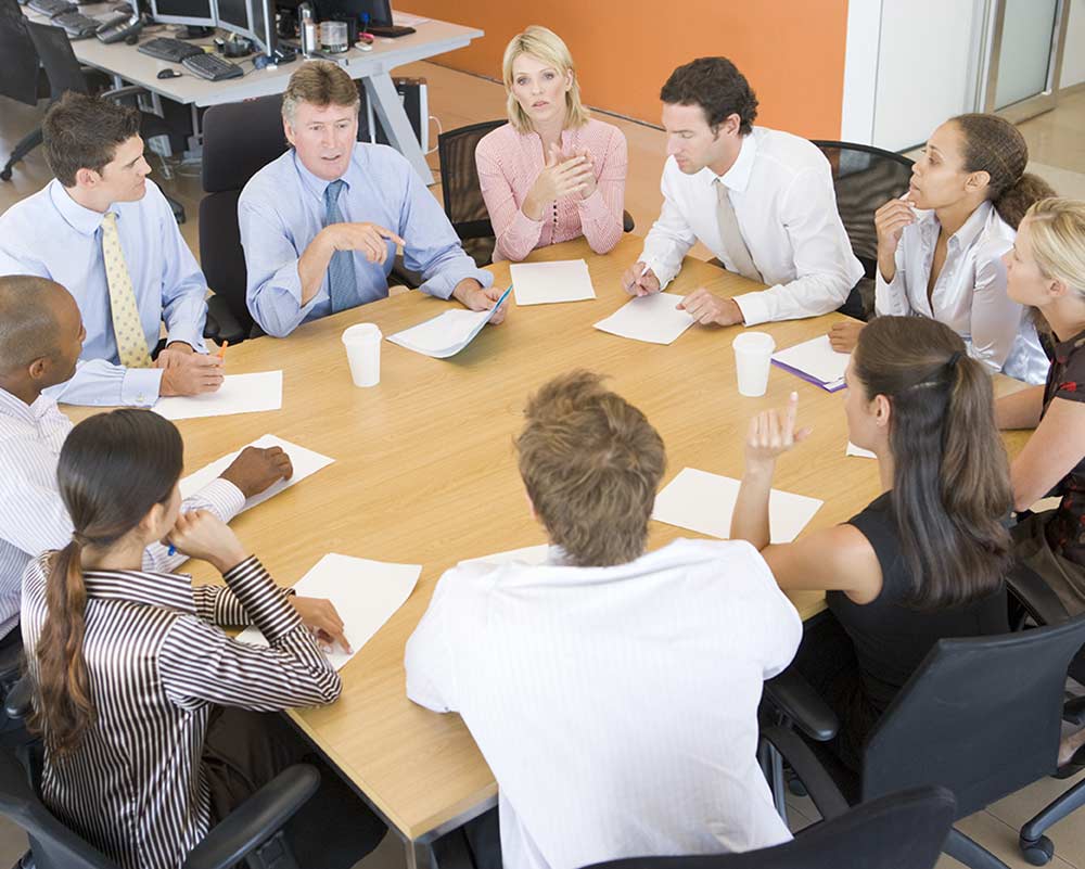 Family business stakeholders and employees meet around a conference table to discuss quarterly planning.